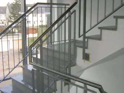 Treppenhaus mit modernen Granitstufen und Metallgeländer in einem Mehrfamilienhaus.